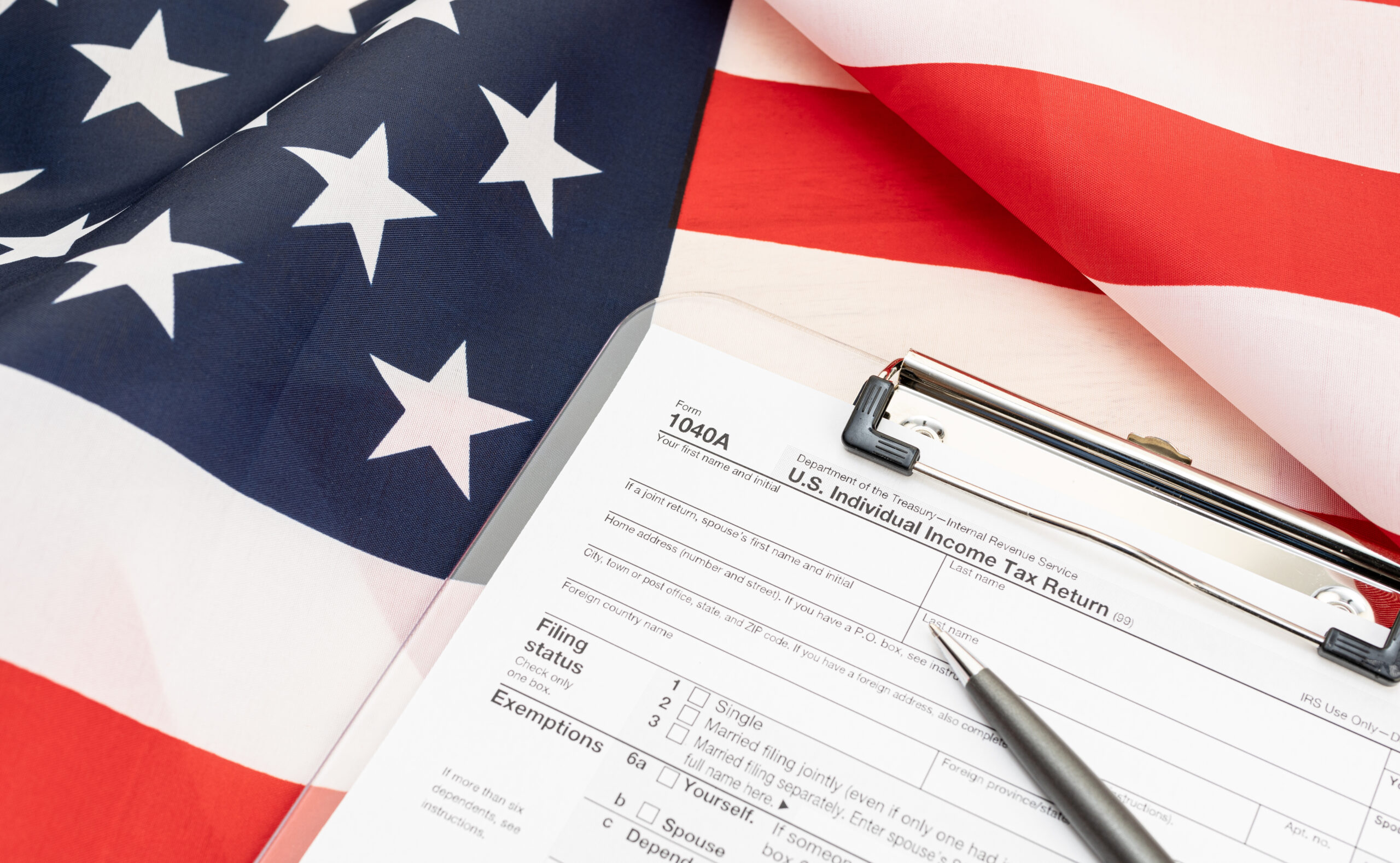 1040A form on clipboard and USA flag at background